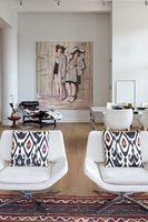 Modern white armchairs and large painting in open plan apartment 