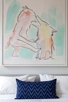 Artwork above modern bed with cushions