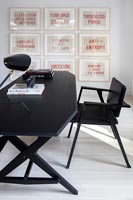 Black desk and chair with display of artwork 
