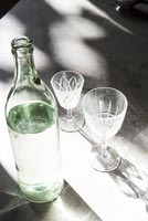Sunlight on glass bottle of water and wine glasses