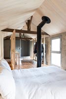 Exposed flue in wooden open plan bedroom 