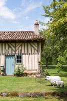 Traditional country house with sheep and lamb sculptures in garden 