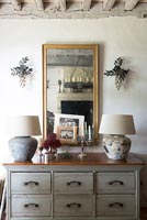 Chest of drawers with lamps and mirror in country house 