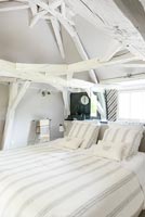White country bedroom with painted wooden beams 