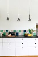 Modern black and white kitchen cabinet with colourful tiled splashback