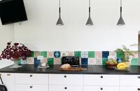 Modern black and white kitchen cabinet with colourful tiled splashback