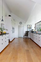 Modern black and white kitchen with wooden floorboards 