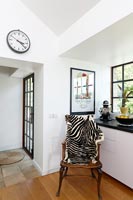 Wooden armchair with zebra blanket in black and white kitchen 