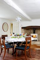 Country dining room with lit log burning stove in large fireplace 