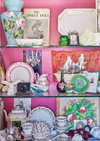Displays and collectibles on glass shelves with pink painted walls 