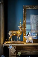 Golden stag ornament and star lights on mantelpiece 