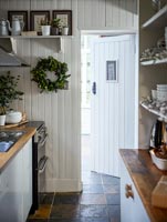 Wood paneled galley kitchen with Christmas wreath on wall white 