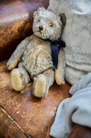 Old teddy bear toy on leather armchair
