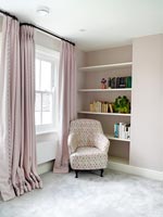 Armchair by window and shelving in bedroom 