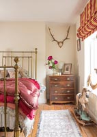 Country bedroom with wall mounted antlers and vintage rocking horse toy 