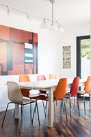 Contemporary dining room with different coloured chairs 