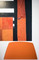 Contemporary colourful painting behind orange chair