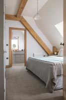View through door to bathroom in bedroom with wooden beams 