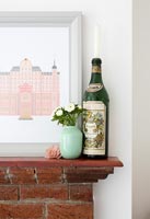 Vintage bottle of Martini and vase of flowers on mantelpiece 