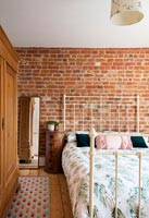 Modern bedroom with exposed brickwork and cream iron bed