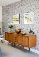 Vintage sideboard next to wallpapered feature wall in dining room 