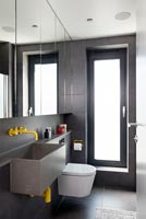 Dark grey contemporary bathroom with bright yellow taps and pipework