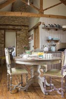 Circular table with painted chairs in country kitchen diner 