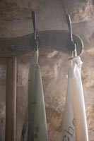 Wooden coat hanger on stone wall with variety of silk scarves 
