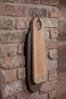 Wooden chopping boards on hook by exposed brick wall 