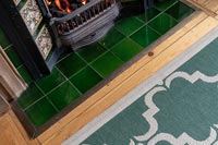 Detail of fireplace with rug and wooden floor