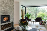 Lit fire in contemporary living room with glazed window and view of garden