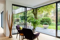 Armchairs facing glazed living room wall with views to woodland garden 