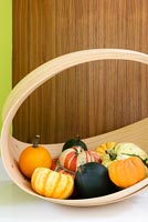 Variety of squashes and pumpkins in curved wooden basket 
