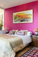 Vivid pink feature wall and colourful painting in modern bedroom 