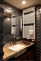 Black brick style tiling in modern bathroom with marble sink