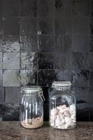 Glass storage jars next to black wall 
