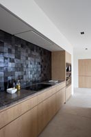 Contemporary kitchen with black tiled splash back