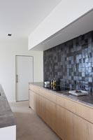 Contemporary kitchen with black tiled splashback