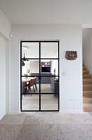 View from hallway to kitchen through internal black framed glass door 