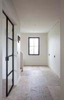 Stone floor in minimal hallway with black framed window 