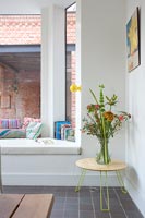 Large window seat and side table with flowers in vase 