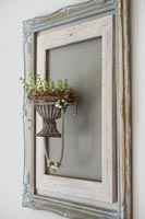 Empty picture frame painted wall and plant holder 