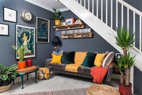 Sofa under stairs in colourful modern open plan living room 