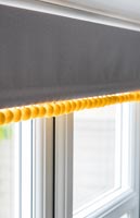 Modern grey roller blind with yellow bobbles 