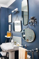 Display of mirrors on dark blue painted wall in lassic bathroom 