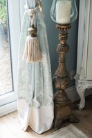 Curtain and tie next to large candle stick 