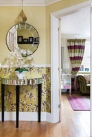 Modern hallway with colourful floral wallpaper and mirrored furniture 