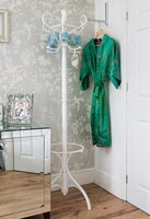 White hat stand in bedroom nest to wardrobe and dressing gown 