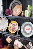 Plates and collectibles on shelves of black dresser 