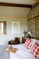 Exposed stone wall and wooden beams in country bedroom 